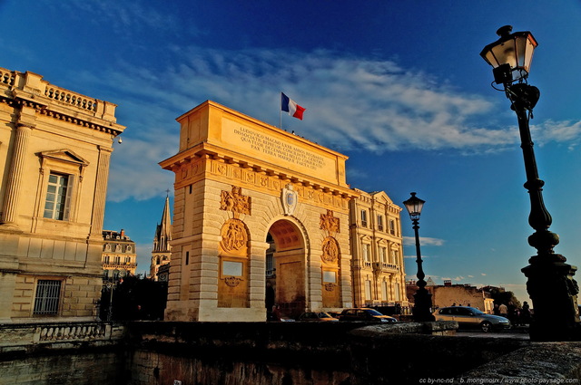 Arc de Triomphe de Montpellier
Cet arc de triomphe marque l'entrée du centre 
historique de Montpellier. Il a été édifié en 1691
à la gloire de Louix XIV.
Mots-clés: montpellier herault languedoc-roussillon paysage_urbain monument arc-de-triomphe rue lampadaires drapeau