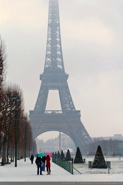 Un hiver à  Paris
Deux touristes aux parapluies colorés se promènent face à  la Tour Eiffel sur un Champs de Mars recouvert par la neige.

[Paris sous la neige]
Mots-clés: cadrage_vertical paris_sous_la_neige neige froid hiver tour_eiffel jardin passant brume brouillard jardin_public_paris